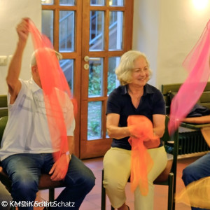 Zwei ältere Menschen mit bunten Tüchern in der Hand